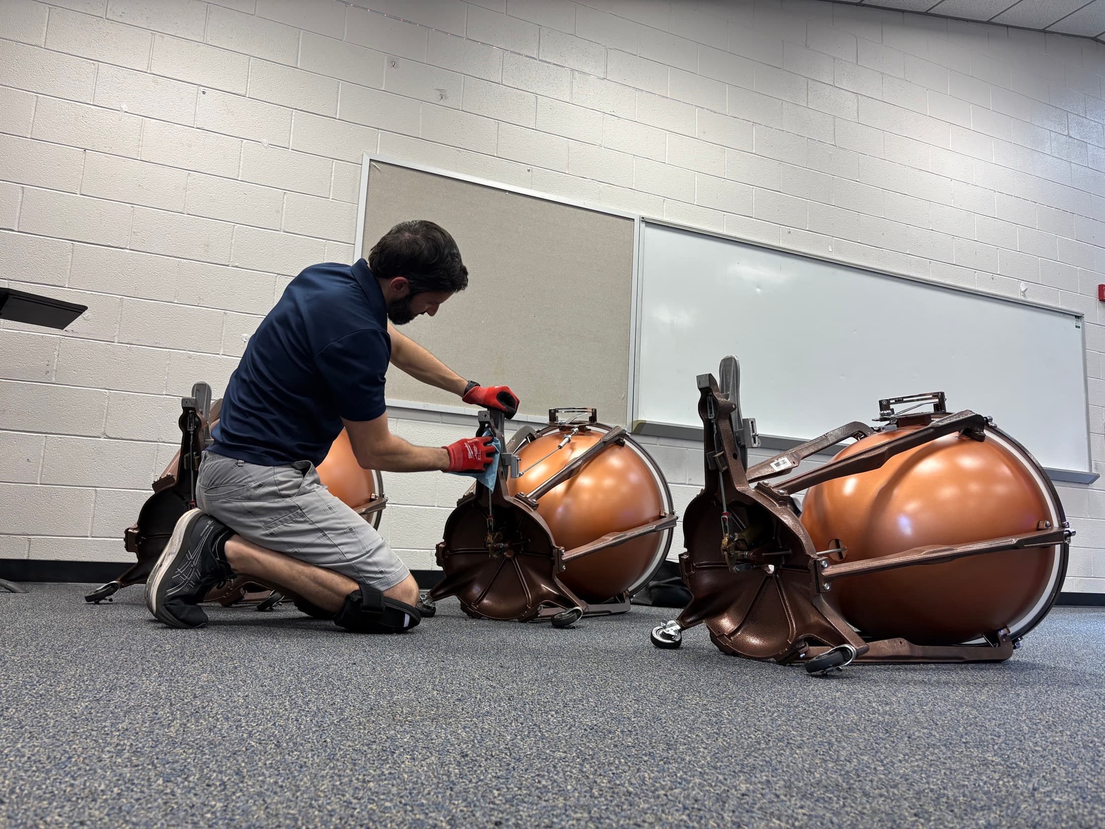 A Bono Percussion technician cleaning the underside of a timpani base during a repair