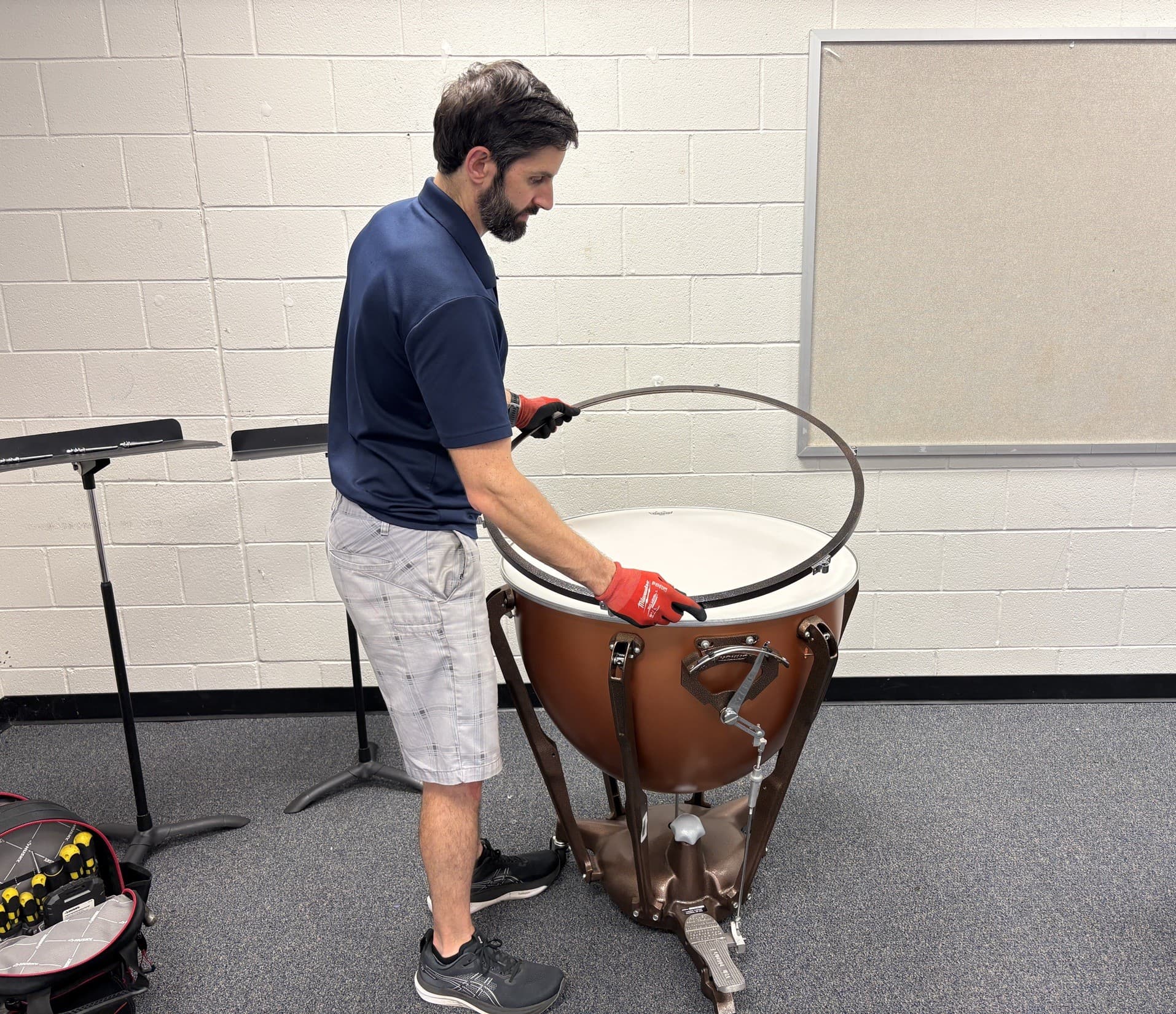 A Bono Percussion technician installing the counter hoop on a timpani in a school band room