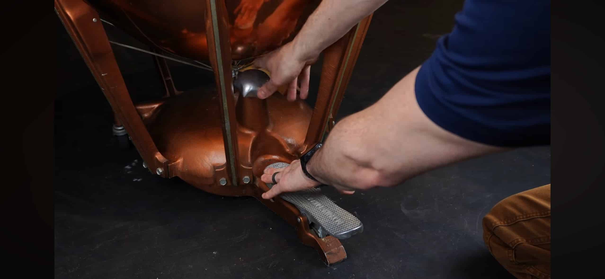 Hands adjusting the spring tension mechanism on a Ludwig timpani