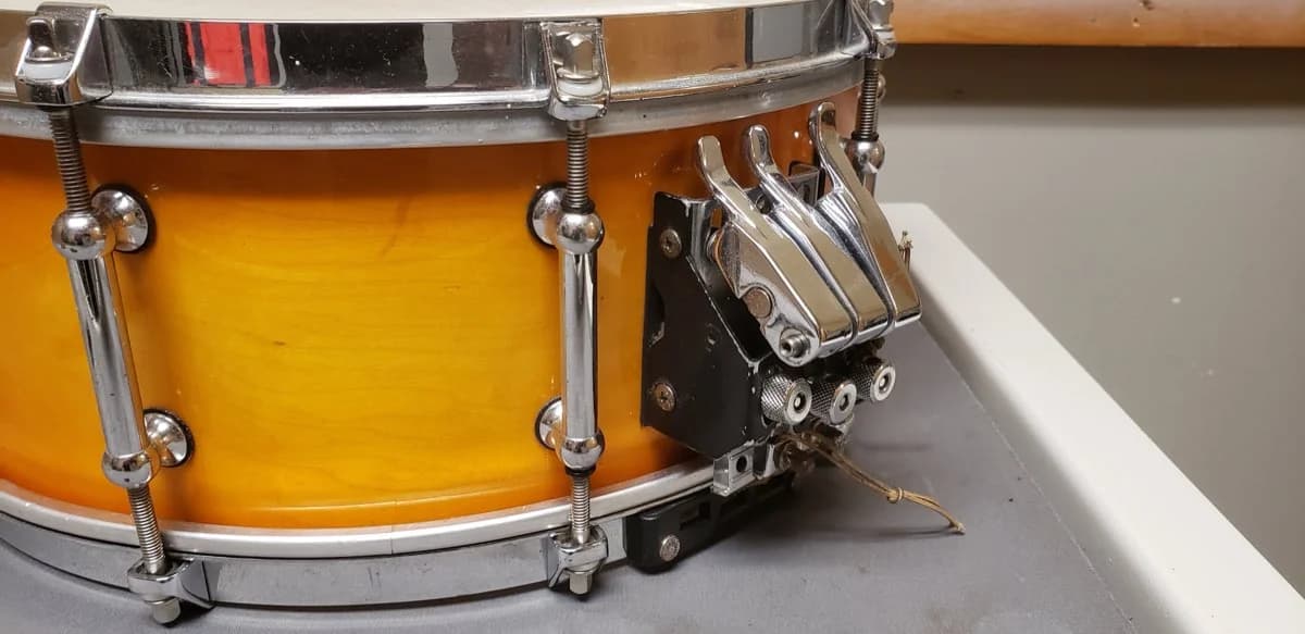 A concert snare throw-off before service, the mechanism worn out and a snare cable frayed and loose