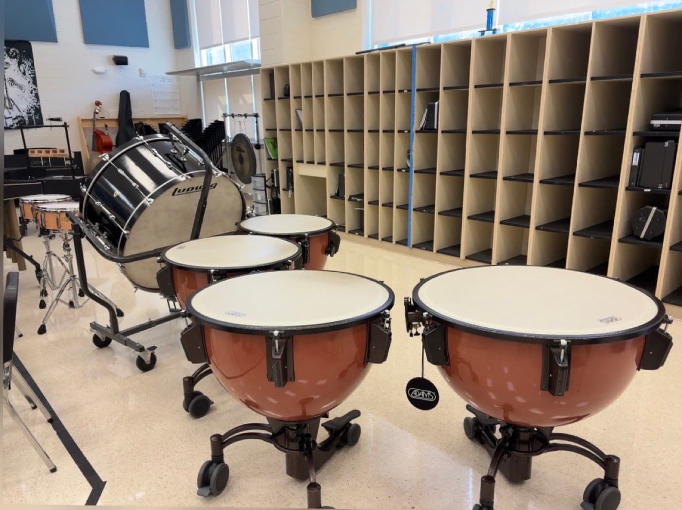A concert bass drum and a set of Adams timpani in a band hall, covered under the Concert Tuning Package