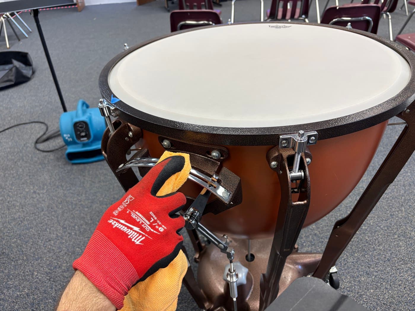 A technician cleaning the chrome hardware on a timpani