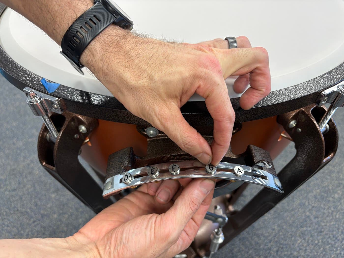 A technician installing pitch indicators on a timpani