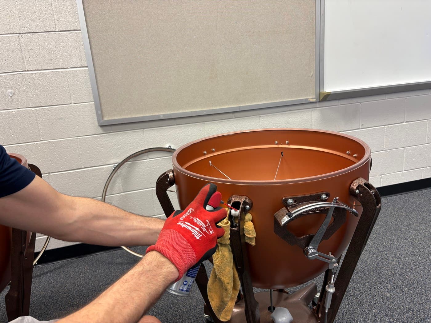 A technician lubricating the moving parts of a timpani pedal mechanism