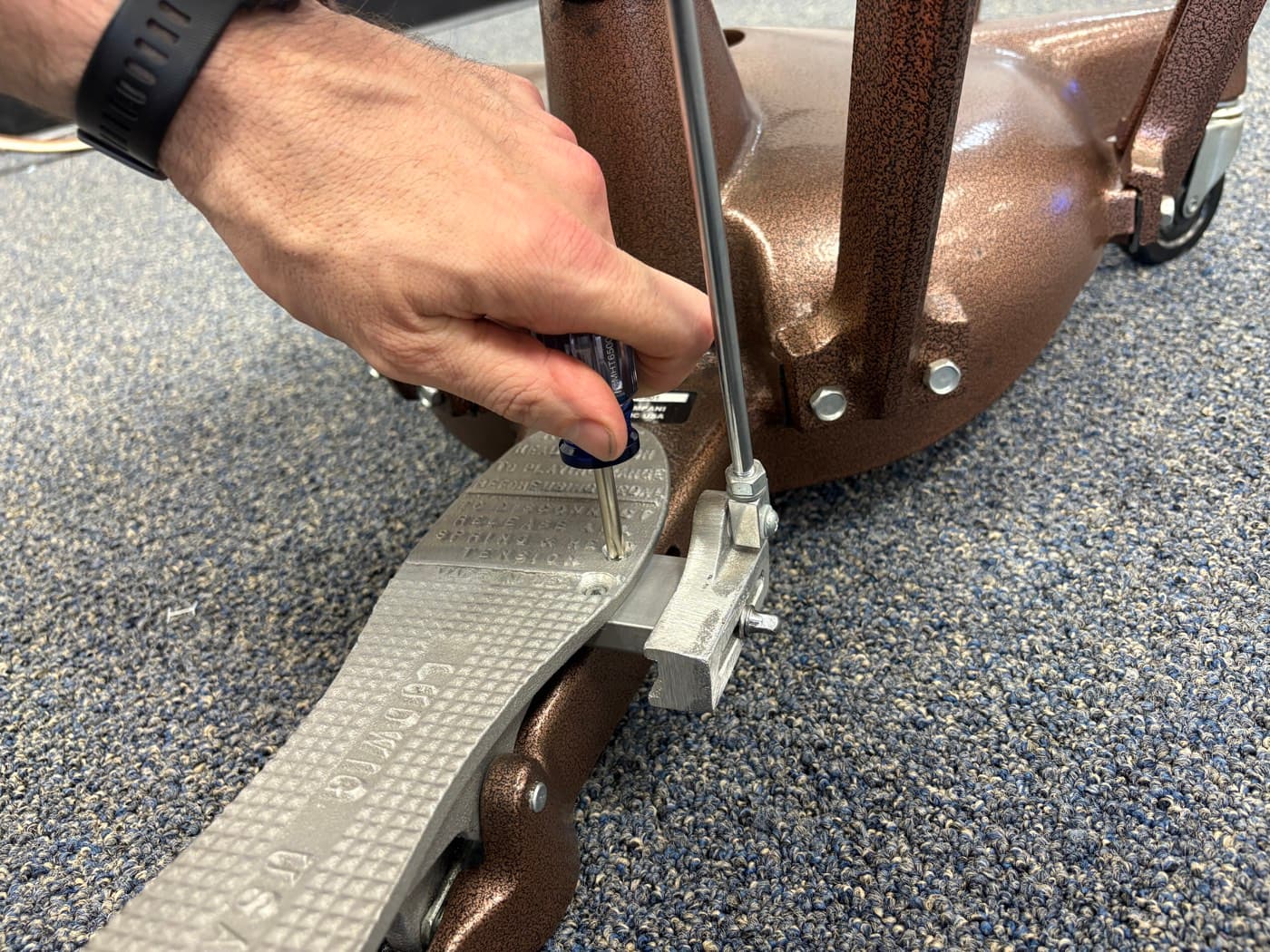 A technician snugging the screws and bolts on a timpani tuning gauge