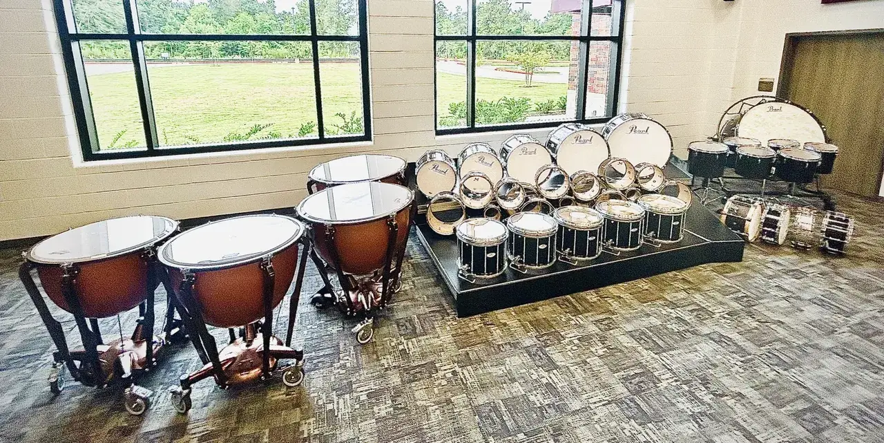 A full concert percussion setup: timpani, concert toms, concert snares, and concert bass drums in a school band hall