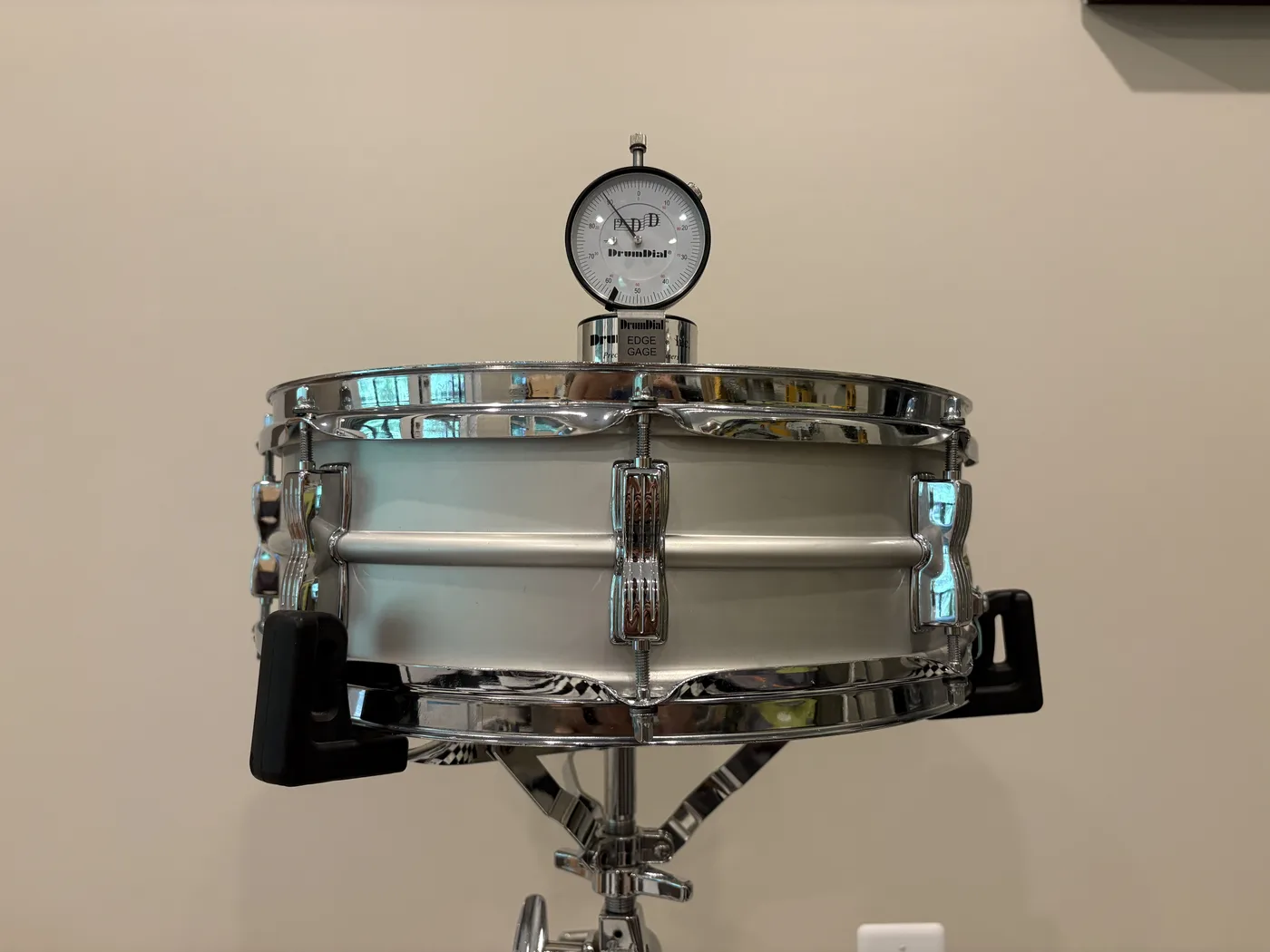A DrumDial gauge clipped onto the rim of a 14 x 5 drum set snare, reading 90 on the batter head