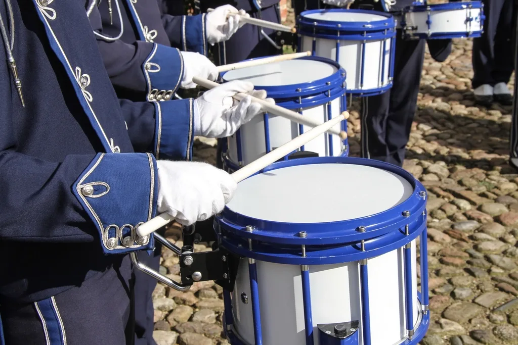 A marching band drumline playing matched snare drums in formation